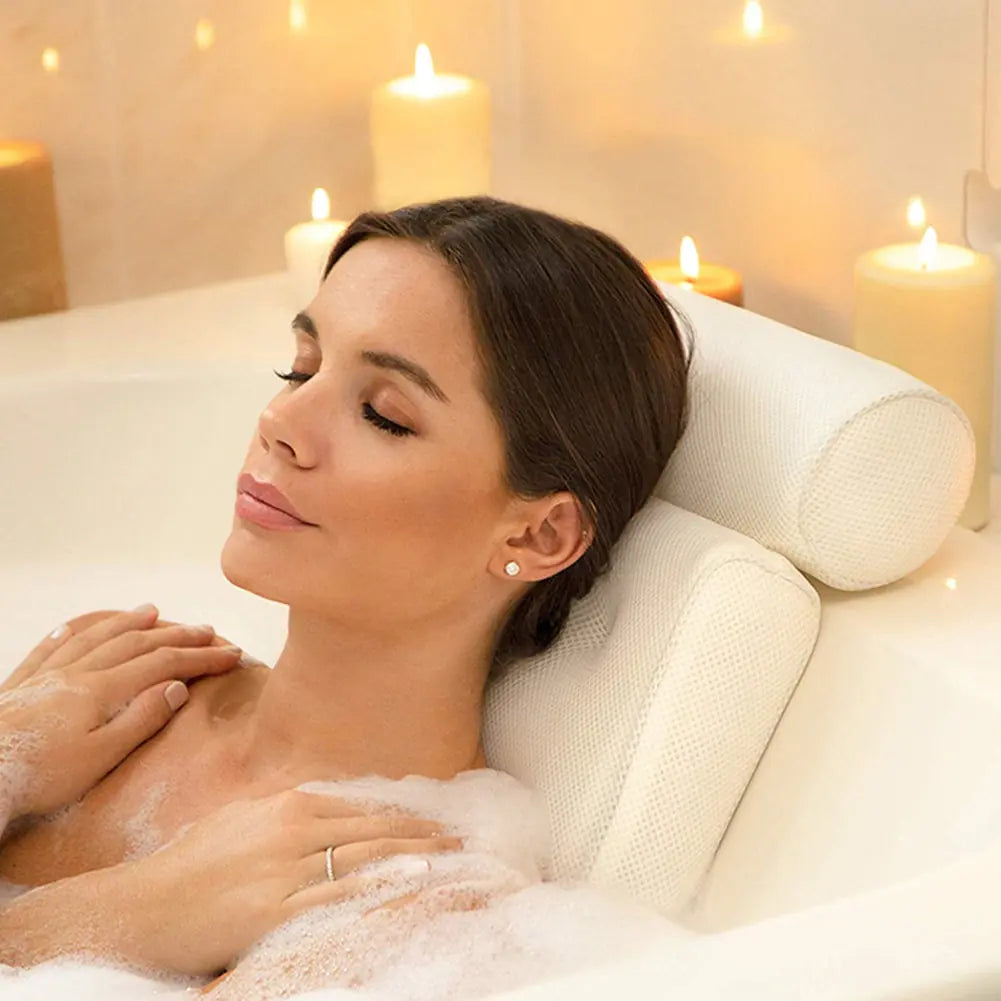 A woman using the pillow in a bubble bath with surrounding candles.