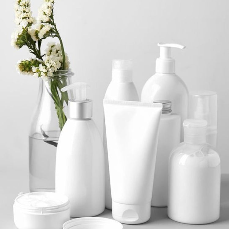 lotions and creams in bottles with a vase of small wildflowers