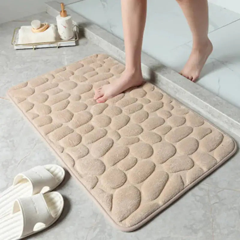 A woman stepping out of the shower onto a  camel-cream-colored Memory Foam Bath Mat