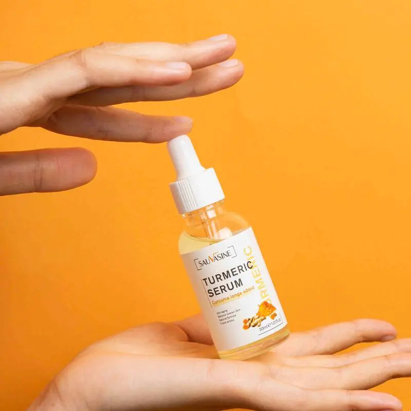 a pair of hands holding a bottle of turmeric serum