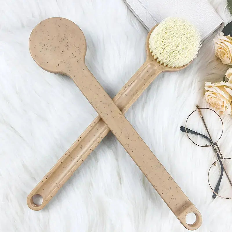 Front and back of long- handled brown bath brush next to flowers and eyeglasses